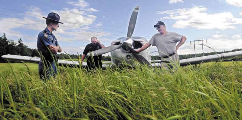 Pastor Todd Bell, right, speaks with Maine State Trooper Eric Verhille, left, as State Police pilot Wayne Ireland speaks with the Federal Aviation Administration Tuesday after Bell had to set his plane down in a hay field in Farmingdale.