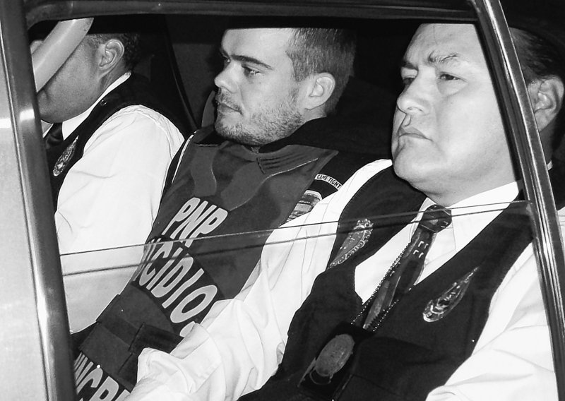 Joran van der Sloot, center, is seen in a police car in Lima, Peru, on Thursday. Van der Sloot confessed to killing a woman in his Lima hotel room on May 30, police said.