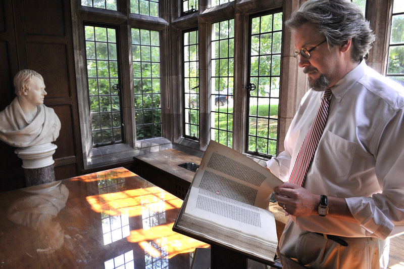 The Rev. John Runkle, conservator of Washington National Cathedral, leafs through a rare Dutch Bible. Runkle is being let go at the end of June, a casualty of the cathedral’s third round of staff cuts to help balance the budget.