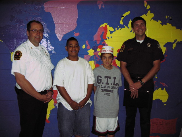 Isaiah Hall, center left, a fifth-grader at Lyseth Middle School in Portland, stands with Brent Rickett on Friday to receive the Everyday Hero award from the Portland Fire Department. On May 25, Isaiah saw Brent choking on a piece of egg during lunch and saved his friend by doing the Heimlich maneuver, which he had learned in health class. The boys are flanked by Fire Chief Fred LaMontagne on the left and Lt. Dan Small on the right.