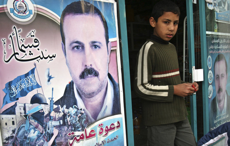 A Palestinian boy walks out of a store covered with posters of assassinated Mahmoud al-Mabhouh, a founder of Hamas' military wing, in Beit Lahiya, northern Gaza Strip. A man wanted in connection with the slaying has been arrested.
