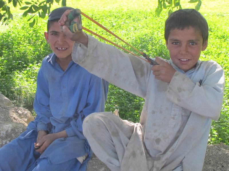 A young Afghan boy shows off his slingshot while he and his friend visit with Bravo Company soldiers Saturday outside Meydani.