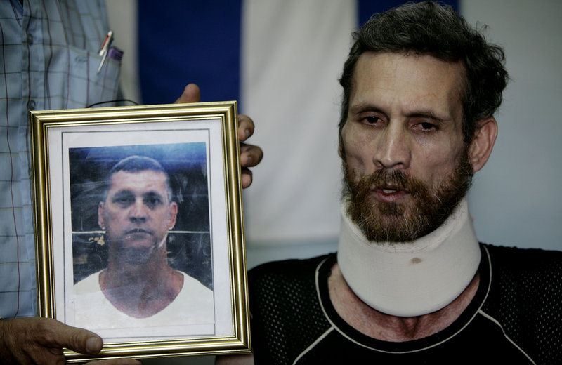 Ariel Sigler speaks with journalists after his release as a political prisoner in Cuba on Saturday. The photograph held next to Sigler depicts him before his arrest.