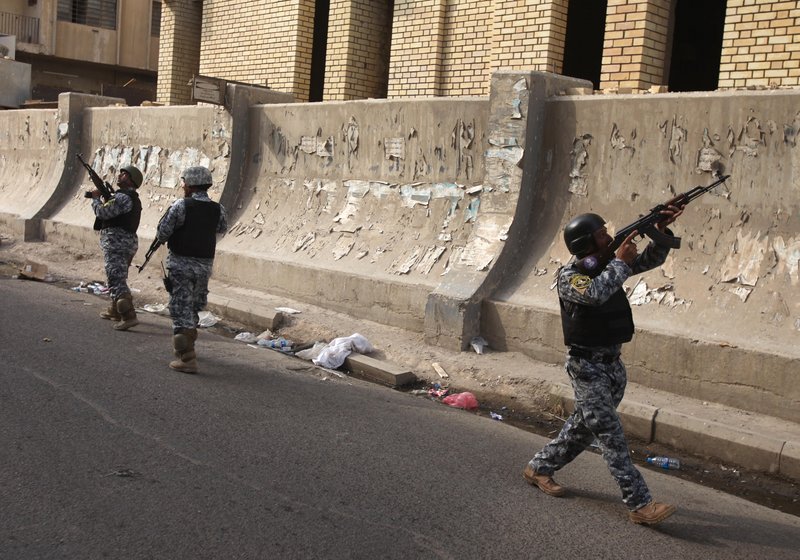 Iraqi policemen prepare to secure the scene of a string of bombings near the Central Bank of Iraq in Baghdad on Sunday. Explosives-packed cars and roadside bombs killed dozens of people in an attack that targeted the Iraqi government’s central bank.
