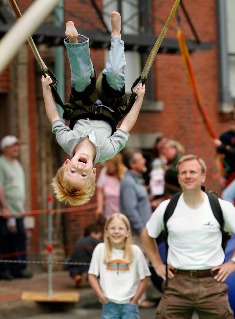 Joseph Dupree, 5, of Cumberland does a flip on the "Monkey Motion" jumper while his sister Charlotte, 9, watches during the Old Port Festival in Portland on Sunday.
