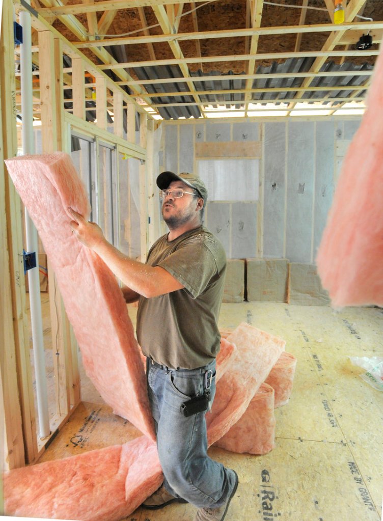 Daniel Gagnon of Lewiston installs insulation in a new home being built in Falmouth. Falmouth had adopted its own minimum energy standards for construction before the state made the new rules.