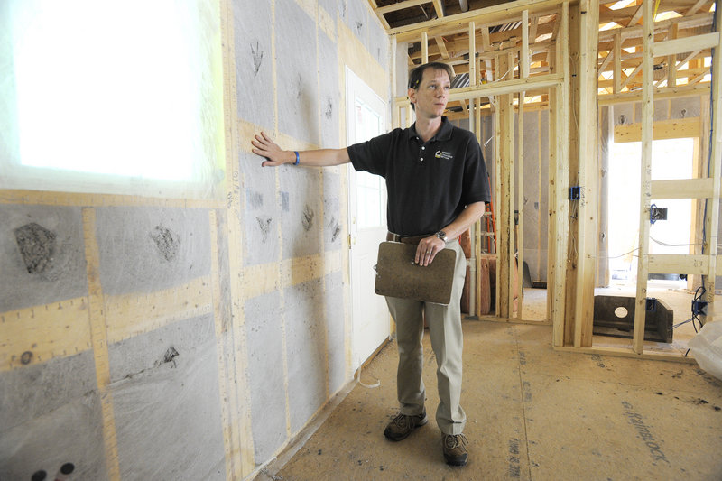 Jerry Brown, assistant manager at Quality Insulation in Yarmouth, points out areas of a building under construction that are affected by changes in new state insulation regulations.