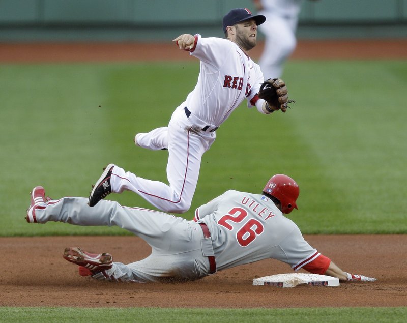 Boston’s Dustin Pedroia leaps as he forces out Philadelphia’s Chase Utley at second base on a double-play ball struck by Jayson Werth in the first inning Sunday at Fenway Park.