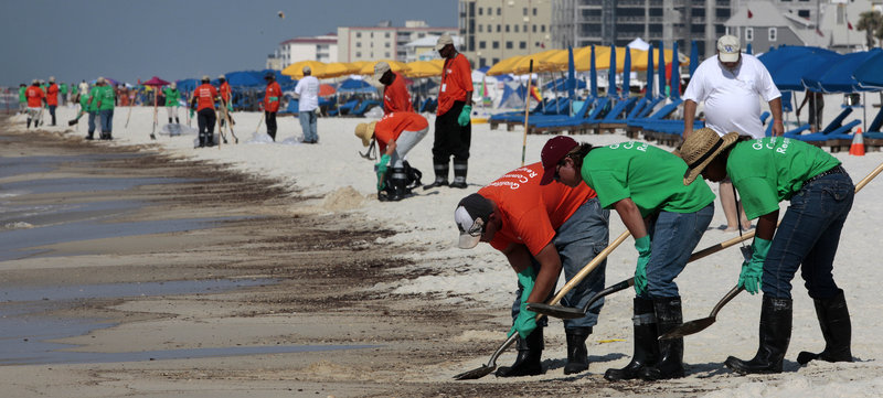Workers hired by BP clean oily deposits from the shore in Orange Beach, Ala., on Saturday. "BP made decisions that increased the risk of a blowout to save the company time or expense," members of a House committee said Monday.