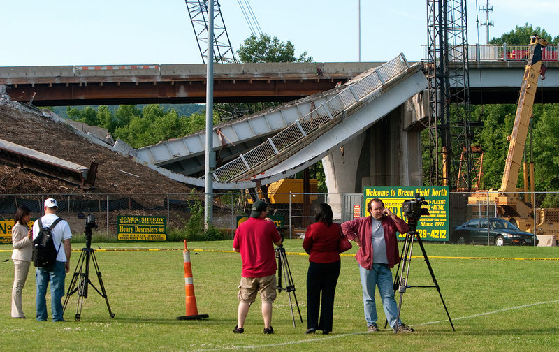 Journalists set up cameras in front of a bridge section that collapsed on Route 63 in Naugatuck, Conn., on Tuesday. One worker, an excavator operator, was critically injured.