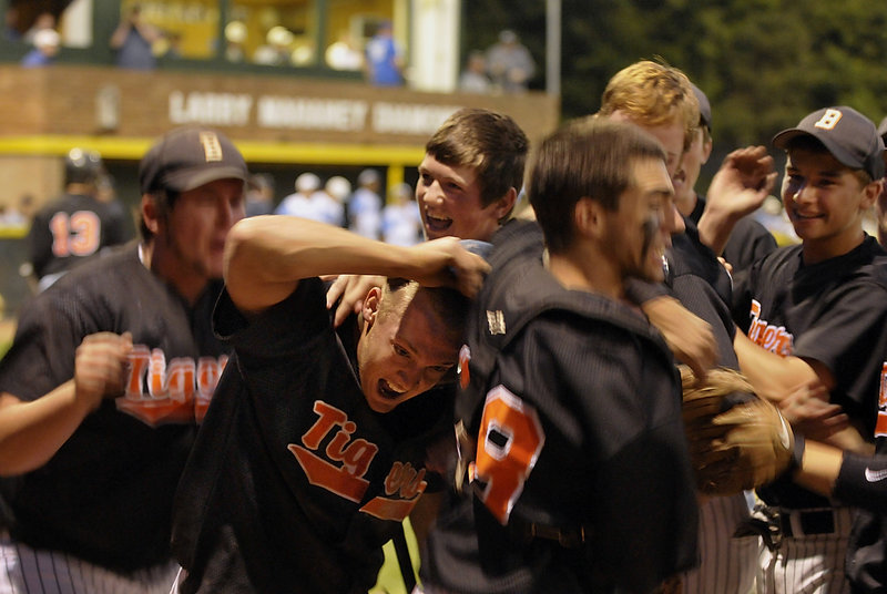 With the Western Class A title in sight, the Biddeford players mob Tyler Parker, second left, after his eighth-inning run gave the Tigers a 4-2 lead against Westbrook on Tuesday.