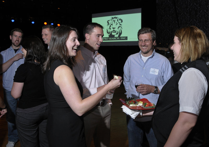 Entreverge chairwoman Susan Pye, left, socializes with Justin Lamontagne and Rob Landry as Lisa Reppucci of Personal Touch Caterers serves appetizers at a business award ceremony at Port City Music Hall in Portland on Wednesday night.