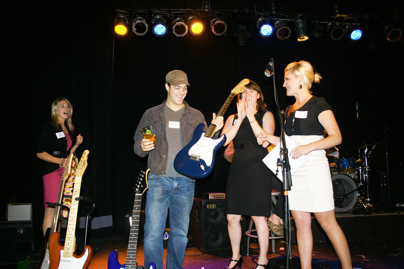 Nathan Deyesso of DSO Creative Fabrications wins the first guitar of the evening as Susan Pye of Merrill Lynch applauds.
