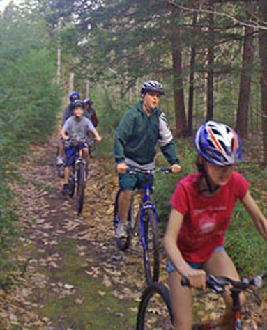 Bonny Eagle Middle School students Katherine Utz, Chris Smith and Will Myrick ride the two miles of cross country trails behind the bus garage at the Buxton school. The trails were created to take advantage of bicycles and other equipment the school has. Physical education teacher Todd Drinkwater is hoping the school can get more equipment for the students to use.