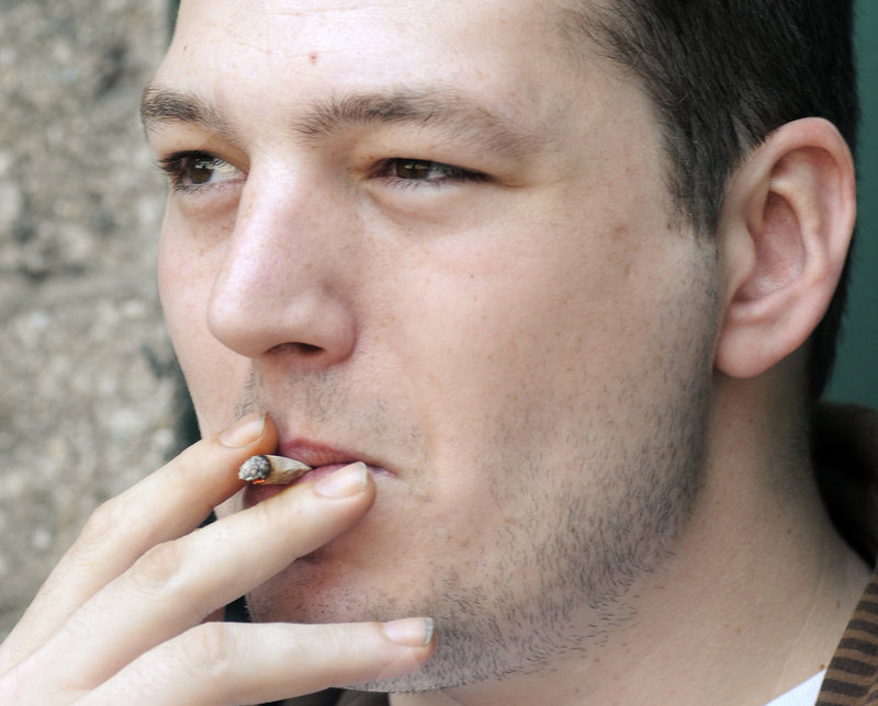 Joe Richards, 27, smokes a cigarette he rolled outside the YMCA on Forest Avenue in Portland. Richards says he started smoking on his 16th birthday after feeling pressure from friends. "My sister is 10 years old, and I tell her, 'Never start smoking,' " he said.