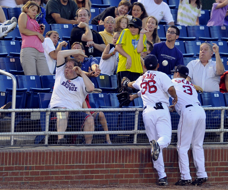 Fans take cover as Sea Dogs third baseman Ray Chang, left, and shortstop Nate Spears reach over the railing in an attempt to catch a foul ball. Chang drove in the winning run in the 10th inning as the Sea Dogs beat the Akron Aeros 8-7 Friday night at Hadlock Field.
