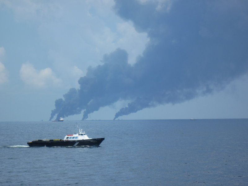 The Mr. Leroy, one of many boats that supply vessels cleaning up oil, nears the Maine Responder as smoke from controlled burns billows on the horizon. Supply boats carry food, water, equipment and passengers.