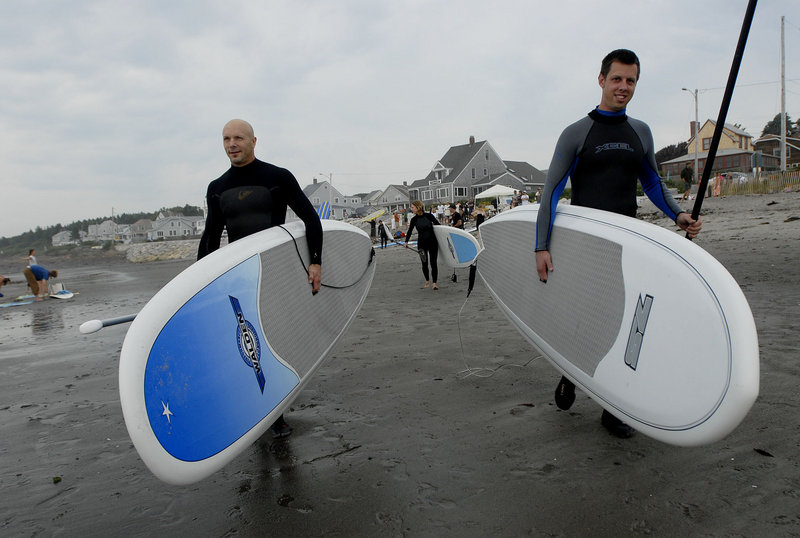 Greg Brown of Freeport, left, and Dylan Nickerson of Scarborough make their way toward the water while surfing at Higgins Beach in Scarborough during the sixth annual International Surfing Day celebration Sunday.