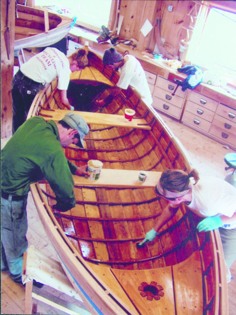 A recent class at the boat shop puts final touches on their wooden creation.