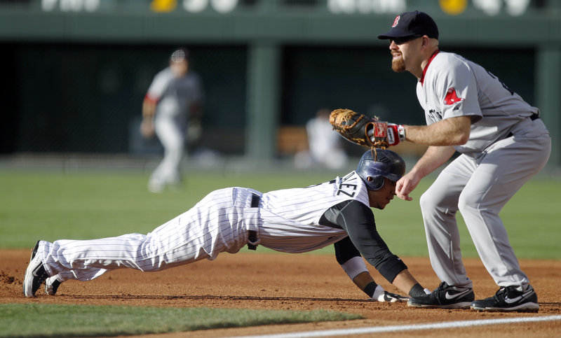 Carlos Gonzalez of the Colorado Rockies dives back to first base Tuesday night as Kevin Youkilis of the Boston Red Sox prepares for a pickoff throw. Colorado won, 2-1.