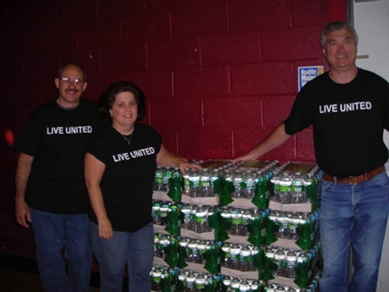 John Cote of Pratt & Whitney, left, Day of Caring Chair Lisa Randall of Kennebunk Savings, center, and volunteer Jeff Fowler provide water supplied by Poland Spring during the United Way of York County's Day of Caring on June 9.