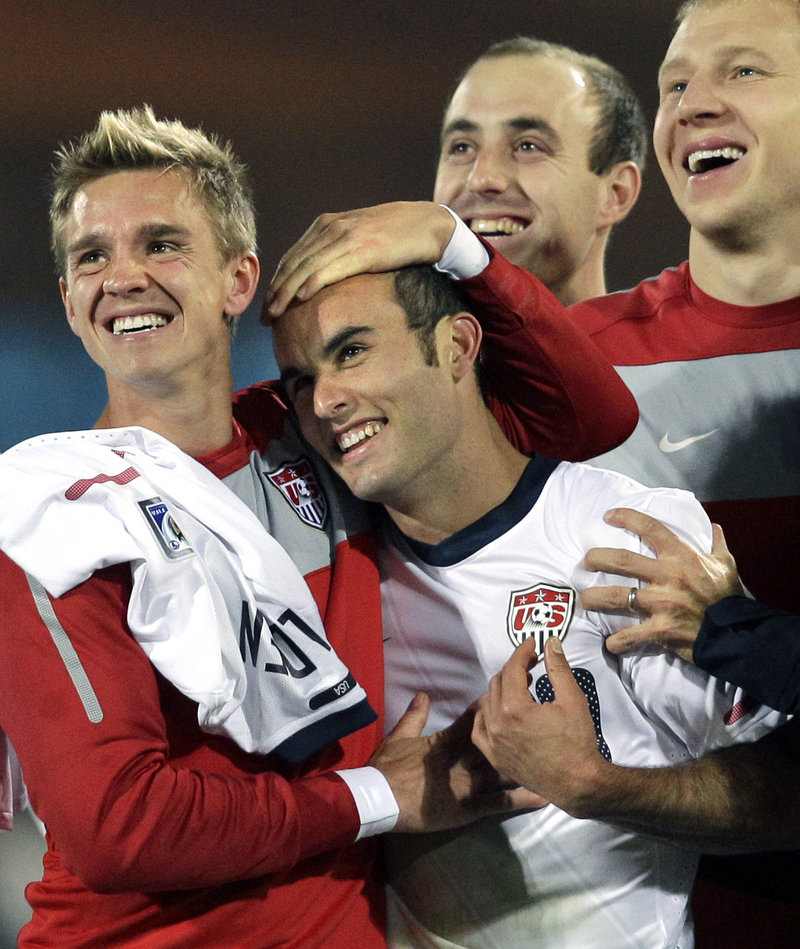 Landon Donovan, center, is hugged by teammate Stuart Holden while watching a replay of Donovan’s injury-time goal Wednesday that gave the United States a 1-0 victory against Algeria and a berth in the Round of 16.