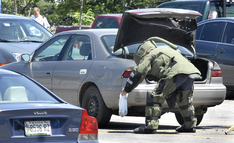 A Maine State Police bomb squad member removes a bag on Friday from the trunk of a Toyota Camry parked in the front parking lot at Southern Maine Medical Center in Biddeford. Authorities said they recovered five pipe bombs from the vehicle parked there by an Alfred man.
