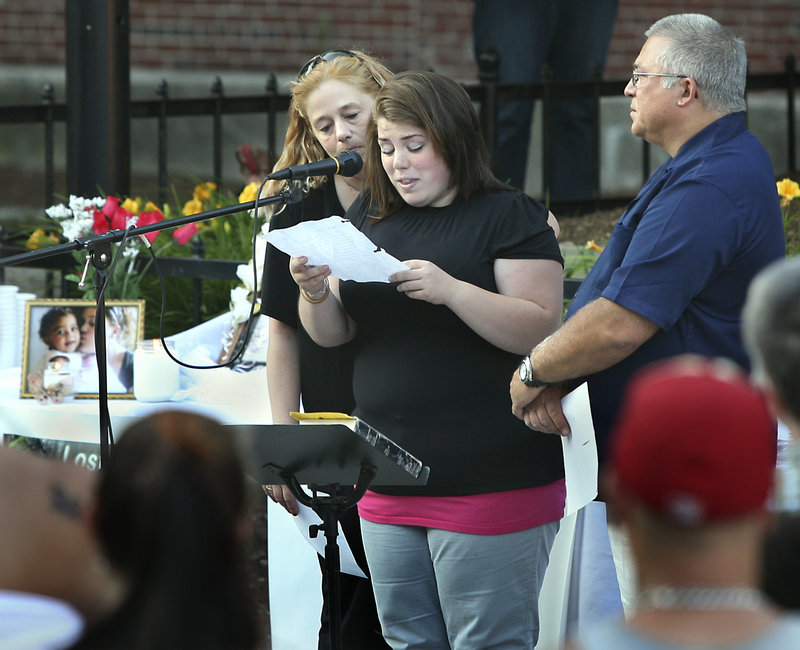 Allie Pertel, the half-sister of Megan Waterman, reads a prayer as Megan’s mother Lorraine Ela and Pastor Mark Drinkwater look on at a candlelight vigil for the missing woman at Congress Square in Portland on Friday.