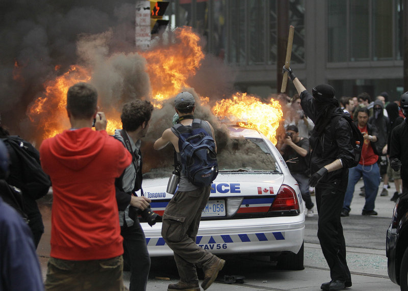 Protesters surround a burning police cruiser during demonstrations in Toronto on Saturday, as the G-20 summit got under way. Some protesters also hurled bottles at police.