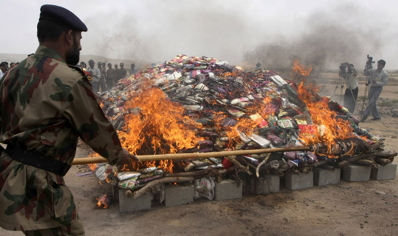 Journalists take photos as authorities burn a pile of confiscated drugs outside Karachi on Saturday. Officials say Pakistani media badly misrepresent the United States in their news reports.