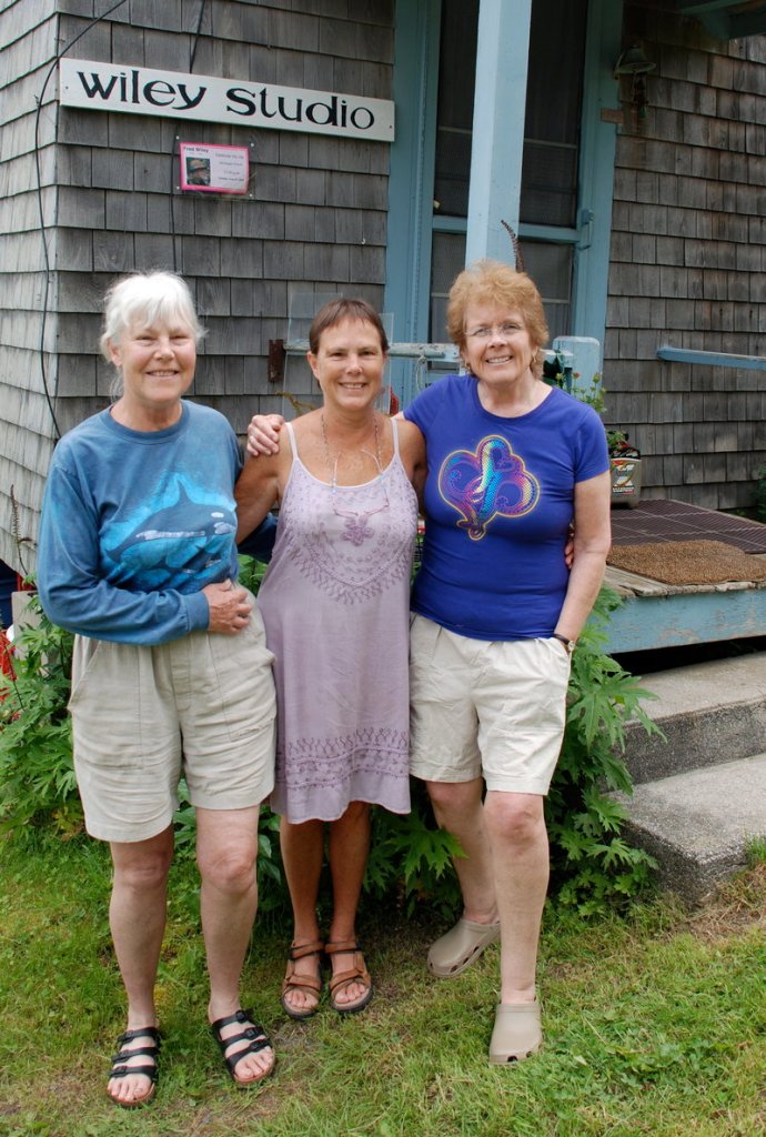 Fred Wiley’s daughters, Dede Wiley, left, and Mim McLellan, center, pose with their “wicked good stepmother,” Faryl Wiley, outside his studio. Fred Wiley first came to Monhegan in the 1960s and loved showing “first timers” around the island.