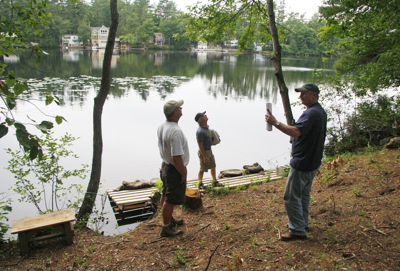 Wayne Whitten, far right, a North Berwick resident on Bauneg Beg Pond, shows Todd Hoffman, center, town Planning Board chairman, and Barry Chase, left, Planning Board member, a seaplane landing ramp he built, during a site walk at the pond Monday.