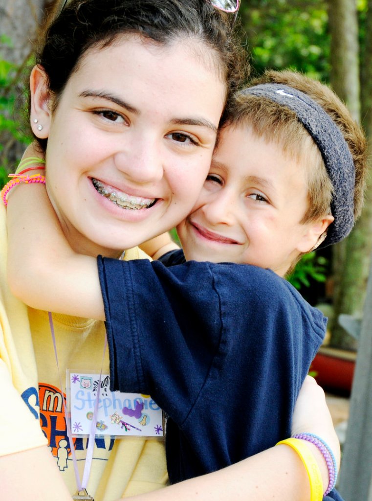 Camp Sunshine volunteer Stephanie Reeves gets a hug from 7-year-old Wesley Young on Tuesday at the campground on the north shore of Sebago Lake. Wesley, of Gorham, was diagnosed with Fanconi anemia when he was a year old and has attended the weeklong camp for children with the rare blood disorder every year since.