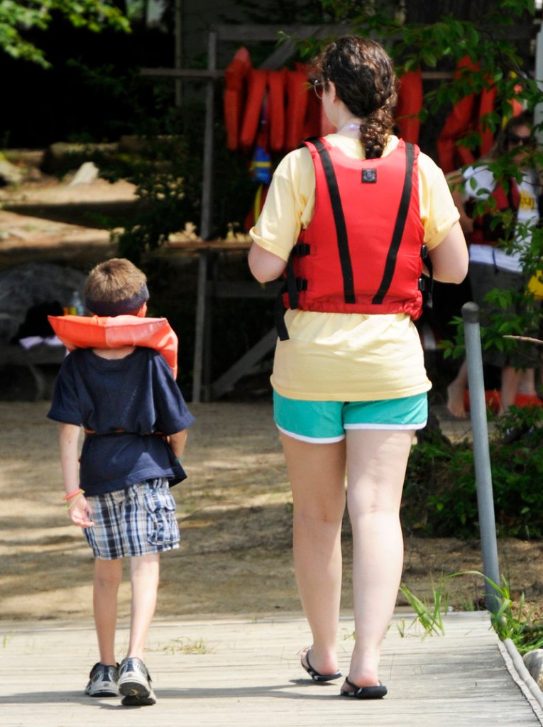 Wesley Young, 7, and volunteer Stephanie Reeves take a stroll after a paddle boat ride during Fanconi anemia week at Camp Sunshine on Sebago Lake.