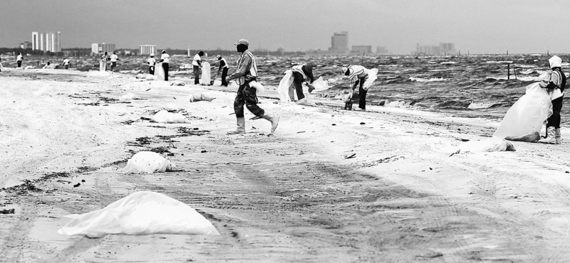 A cleanup crew works to remove tar balls from a Gulfport, Miss., beach Tuesday. From Florida to Louisiana, efforts to skim oil from the water were halted as waves churned by Tropical Storm Alex reached heights of 12 feet in parts of the Gulf. The loss of skimming work combined with 25-mph winds driving water into the coast left beaches vulnerable to being coated with oil.