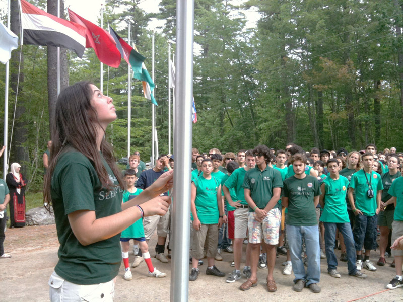 Mary-Kate Johnson, a counselor from New York, raises the Jordanian flag during opening ceremonies at the Seeds of Peace camp in Otisfield. There are 160 campers participating in this first session, which runs for 21 days.