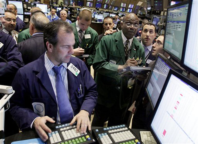 In this file photo, specialist Brian Quinn, left, works at his post on the floor of the New York Stock Exchange. Stock futures and interest rates tumbled today after fresh signs of a global economic slowdown spooked investors.