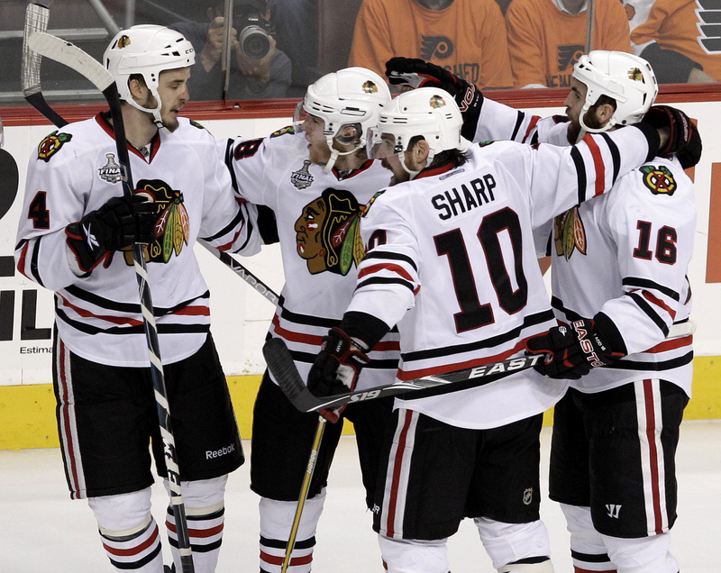 Andrew Ladd, right, celebrates with, from left, Niklas Hjalmarsson, Patrick Kane and Patrick Sharp after scoring for the Blackhawks in their Cup-clinching overtime win.