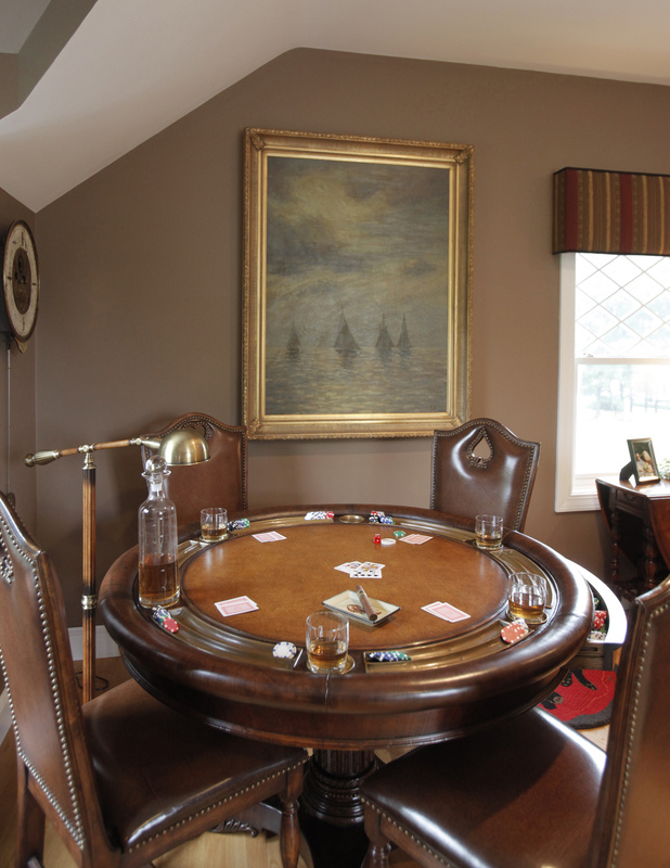 A round poker table with side chairs makes good use of a corner area in a room designed by American Traditions of Portsmouth, N.H.