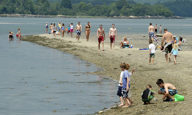 Sunbathers crowd Sandy Point as kids look for crabs during low tide on Cousins Island in Yarmouth. The beach is submerged during high tide so timing is important, according to a regular visitor.