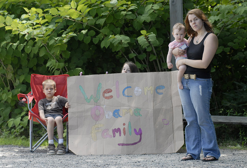 Melissa Abbott watches with hopes of seeing President Obama from her driveway along Route 3 in Bar Harbor along with her children, from left, Alec Zumwalt, 6, Evelyn Zumwalt, 8, holding the sign, and Keira Abbott, 1.