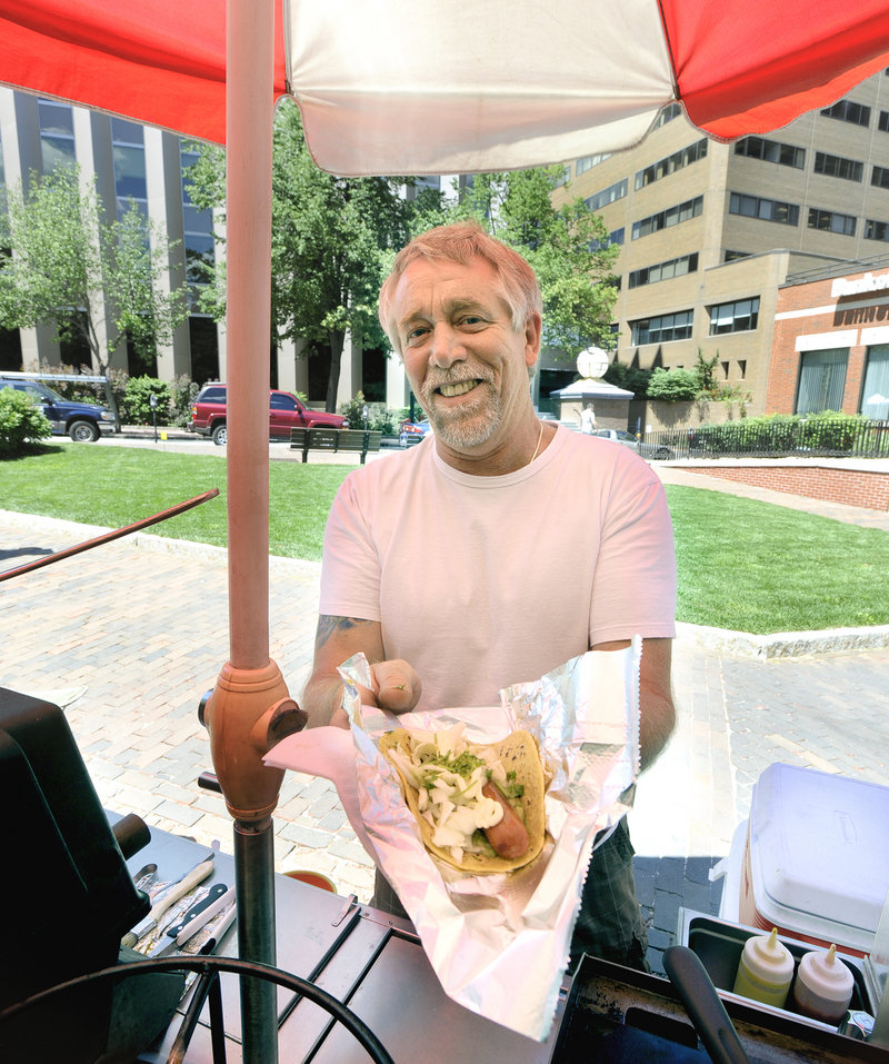 Mike Heathers operates the Baja Dogs hot dog cart in Monument Square in Portland. He's seen here with a Mixta – a grilled beef dog on a corn tortilla with guacamole, green cabbage, mayo and cilantro.