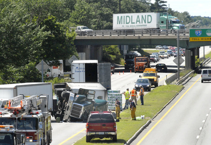Workers unload Rolling Rock beer from a tractor-trailer that rolled over on the spur connecting the Maine Turnpike to Route 1 in South Portland at 1 p.m. Wednesday. The driver, Richard Abram, 54, of Providence, R.I., was not injured in the crash but was transported to the hospital for unrelated issues. Traffic was diverted. There were no charges in the accident.