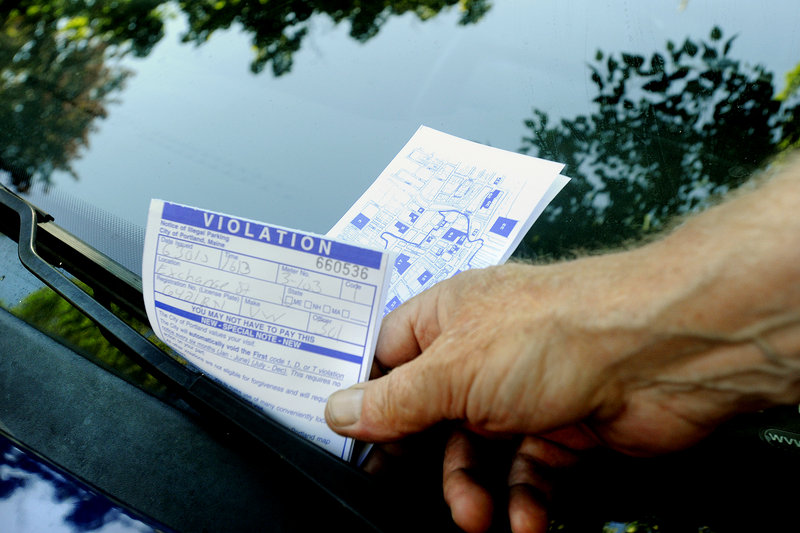 A Portland parking enforcement officer hands out a parking ticket Wednesday on Exchange Street. With the city struggling to balance its budget, starting today, no more minor parking tickets will be forgiven.