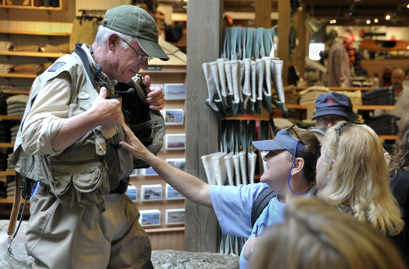 Ken Estes of L.L. Bean lets Ona Stewart feel his fishing outfit as part of a visit to the store by people who are blind and deaf and the students learning to interpret and support them.