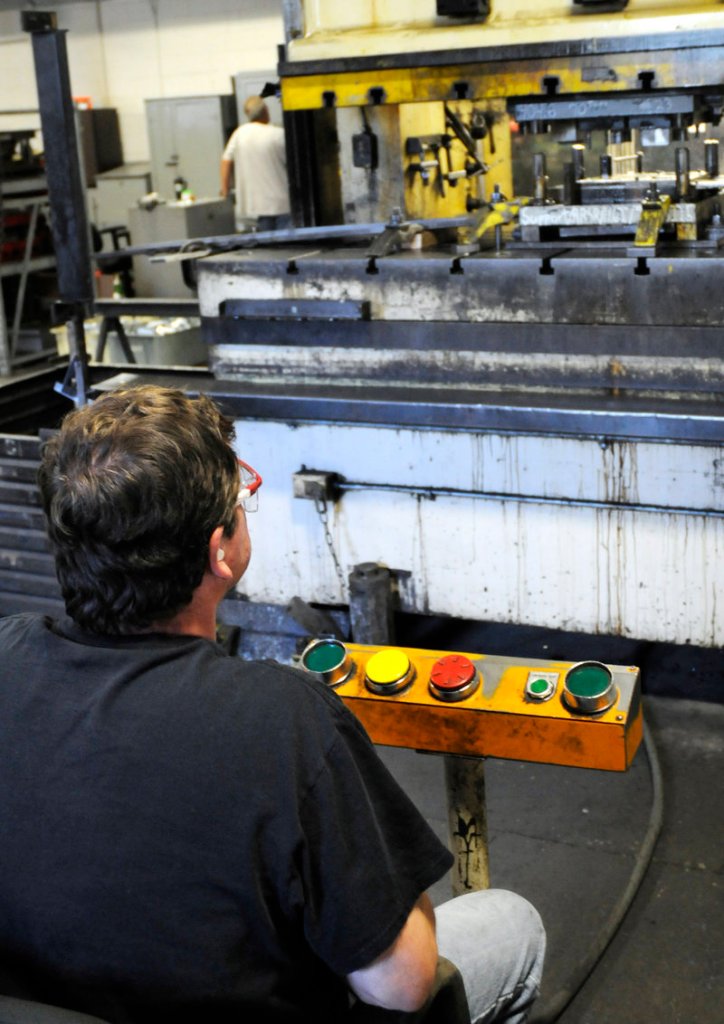 Kevin Hobart, left, operates a 200-ton press that stamps and forms metal components.