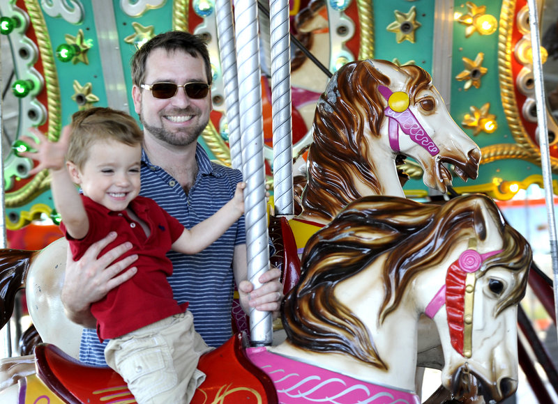 Two-year-old Sawyer Blake and his father, Sterling Blake, of Bath ride the merry-go-round at the 38th annual Bath Heritage Days on Saturday.