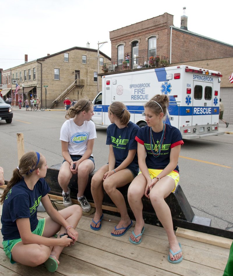 Parade-goers sitting on a float watch an ambulance pass after two horses trampled people at a Fourth of July parade in Bellevue, Iowa, Sunday. A 60-year-old woman later died.