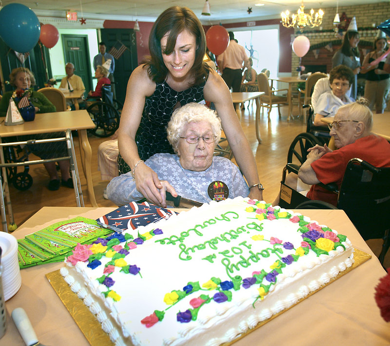 Charlotte Farrin, 102, cuts her birthday cake with the help of Mandy Johnson, director of recreational therapy at Evergreen Manor in Saco, during Farrin's party on Monday.