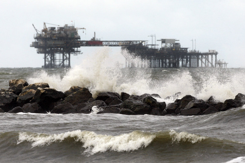 An oil rig is seen beyond a jetty at Fourchon Beach in Port Fourchon, La., on Monday. Despite extensive study by a host of experts, it has been hard to get a handle on just how much ecological damage the BP spill has caused in the Gulf of Mexico.
